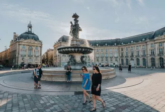 Place de la Bourse à Bordeaux avec sa fontaine monumentale au centre, entourée de bâtiments classiques du XVIIIe siècle et de visiteurs